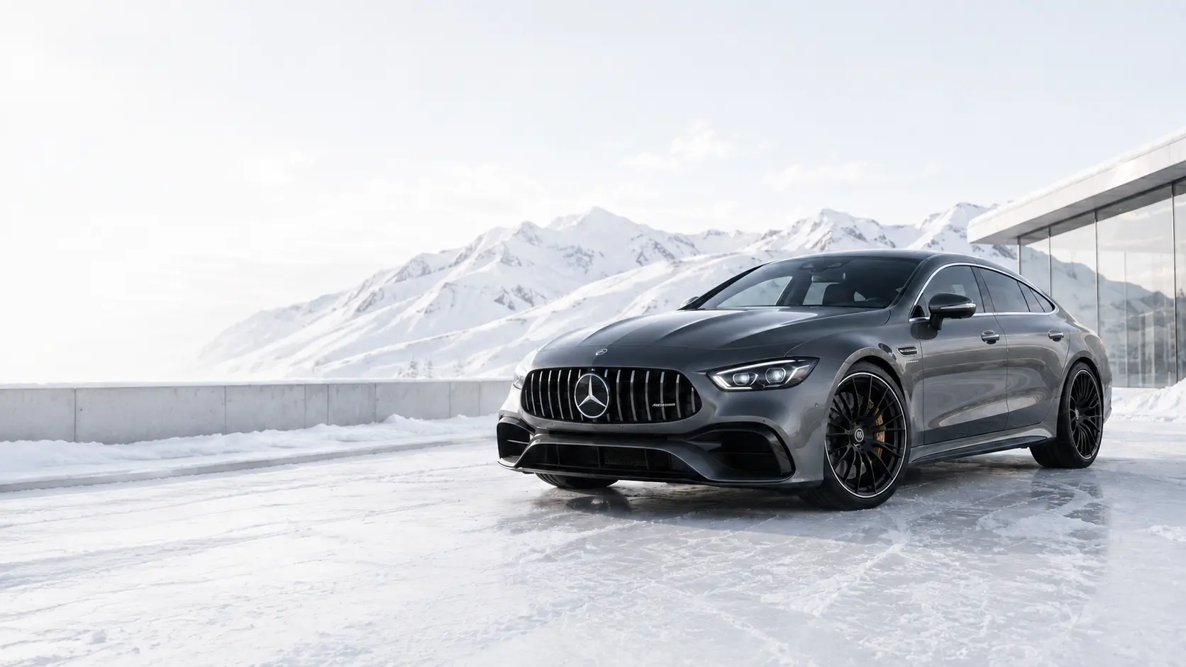 Серый Mercedes на фоне заснеженных гор и современного автосалона