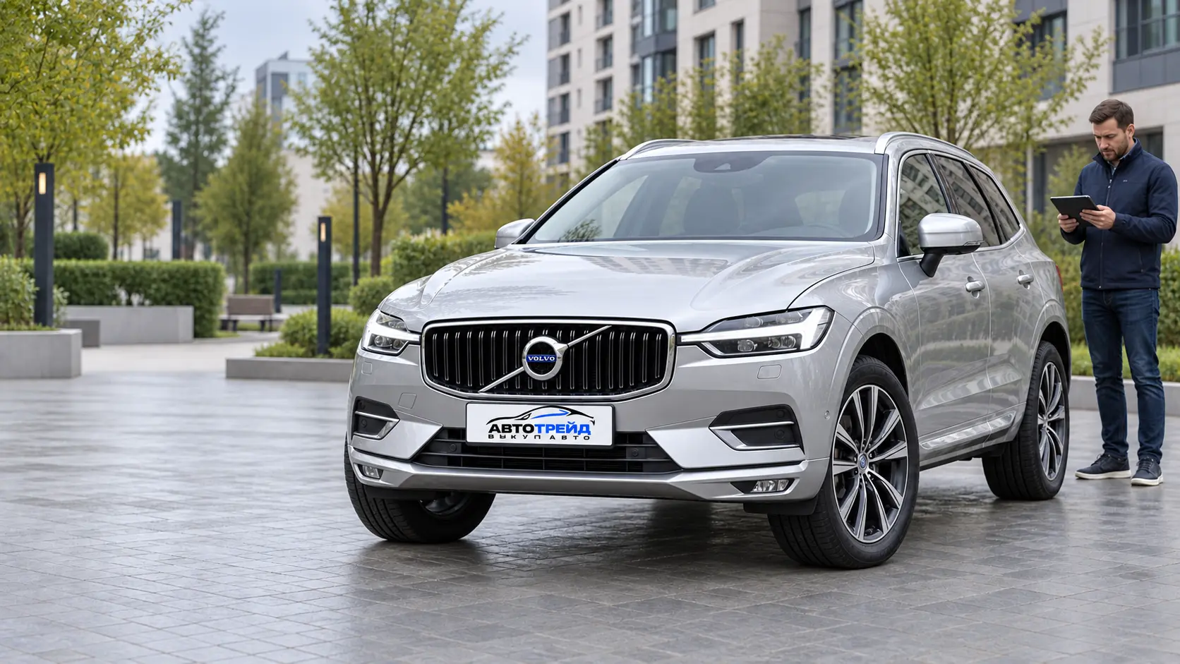Осмотр серебристого Volvo XC60 на городской стоянке; рядом специалист с планшетом